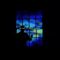 A dark image, with only a window of what appears to be digital screens providing the only light. The screens are lit up with a mix of deep blue, aquamarine, yellow, and highlighter green. The silhouette of a person with short hair reaches for the window of screens.